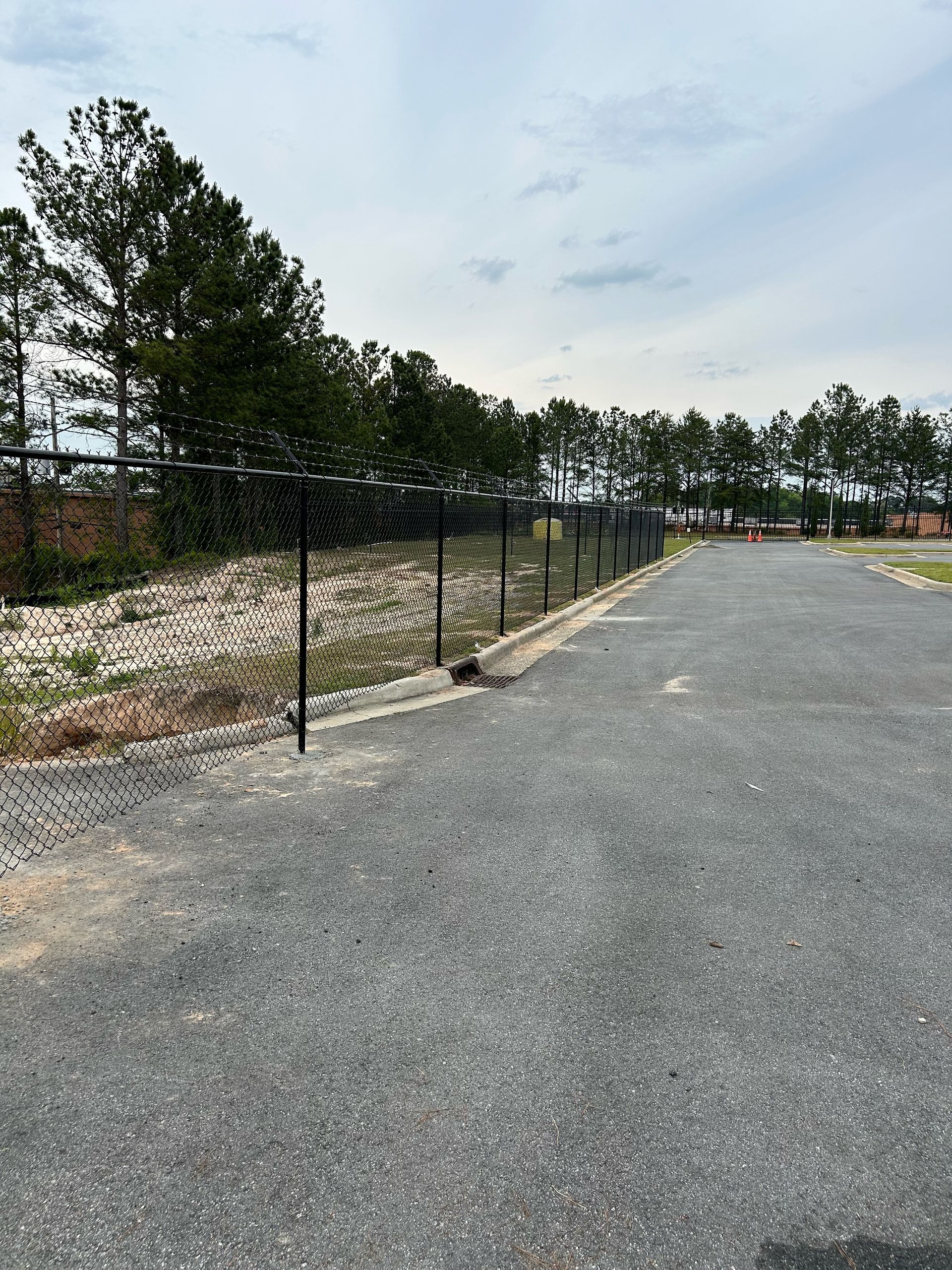 A road with a fence and trees on the side of it.