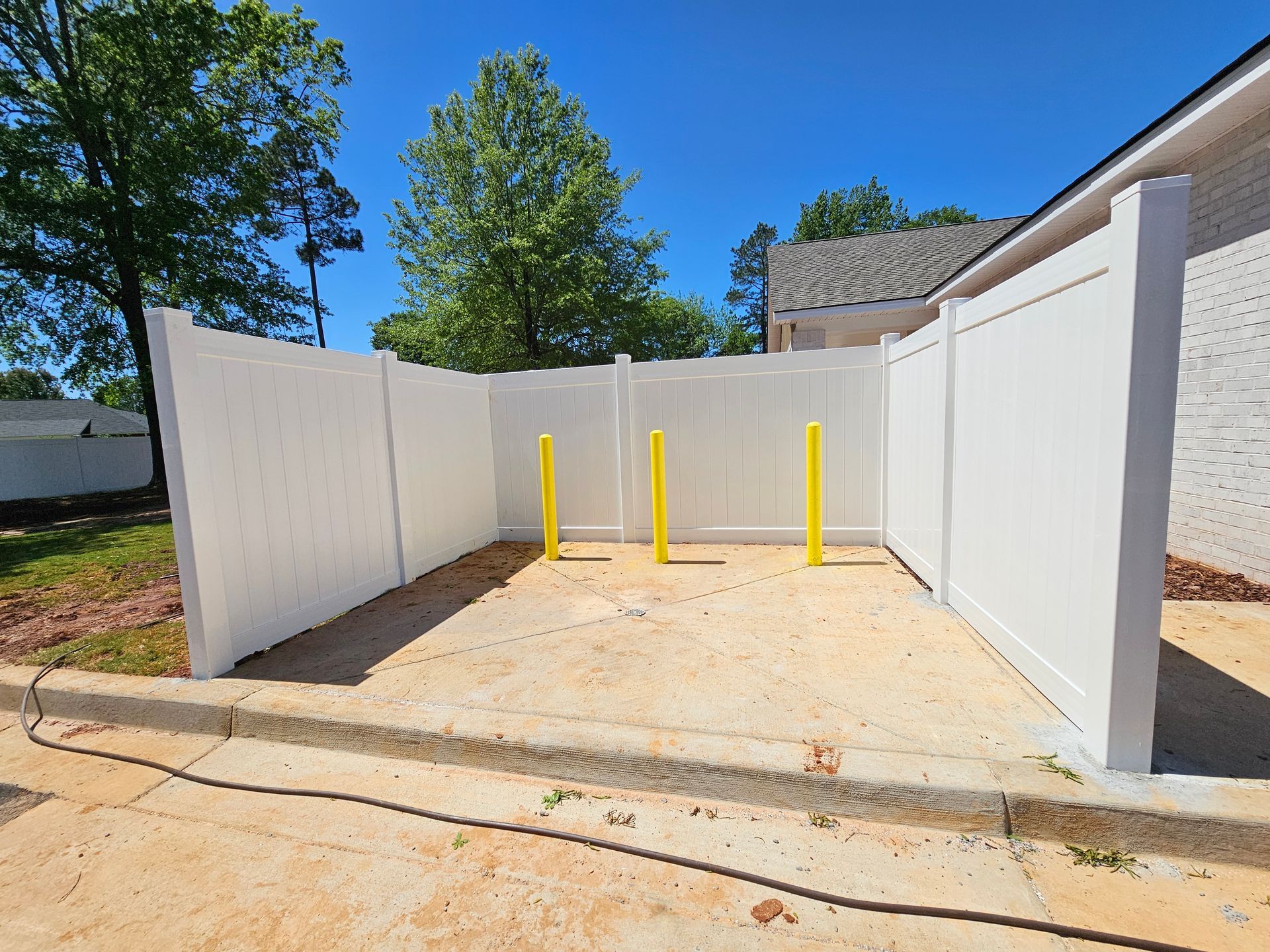 A white fence with yellow poles in front of it
