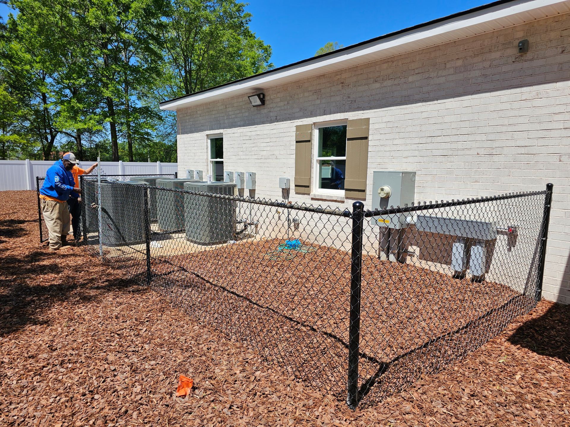 A chain link fence is being installed in the backyard of a house.