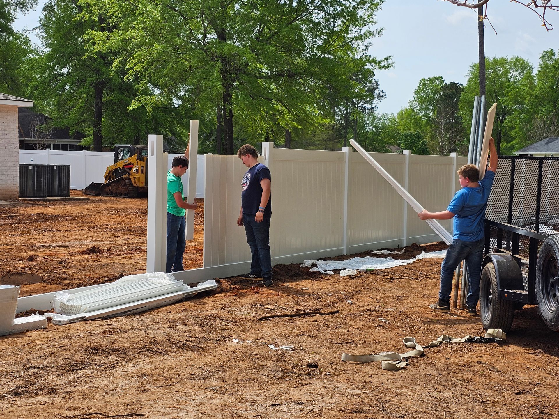 Two men are working on a fence in a dirt field