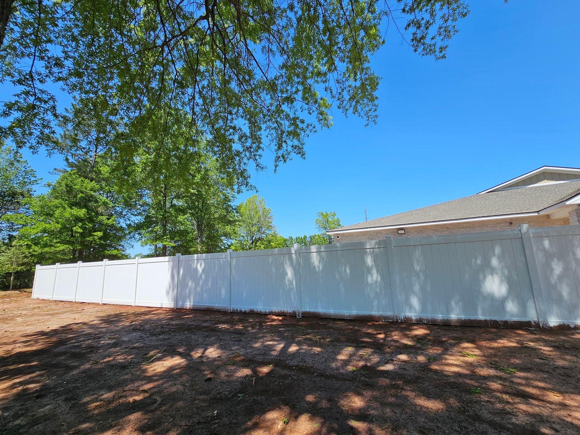 There is a white fence in the backyard of a house.