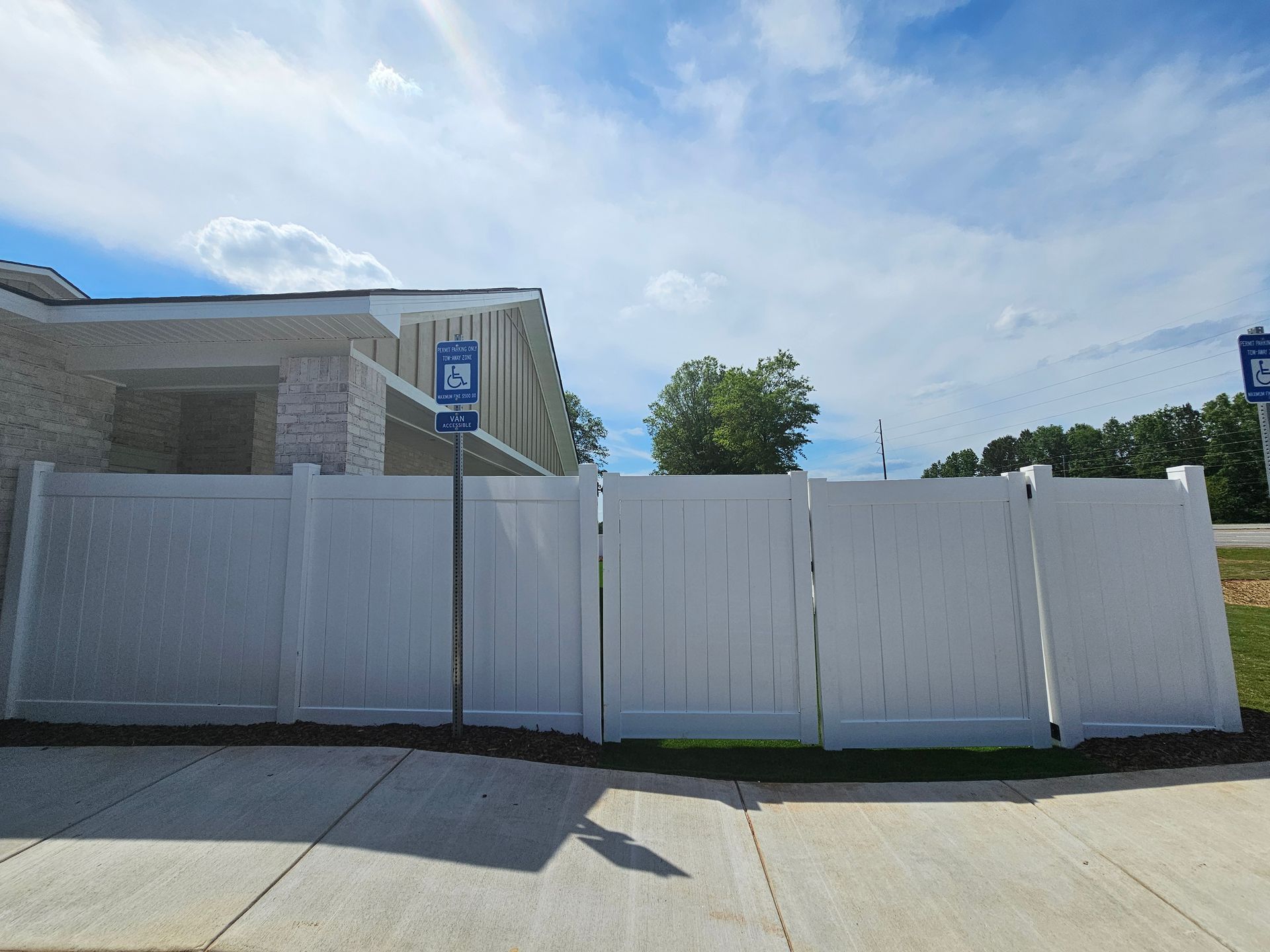 A white fence surrounds a handicapped parking spot in front of a house.