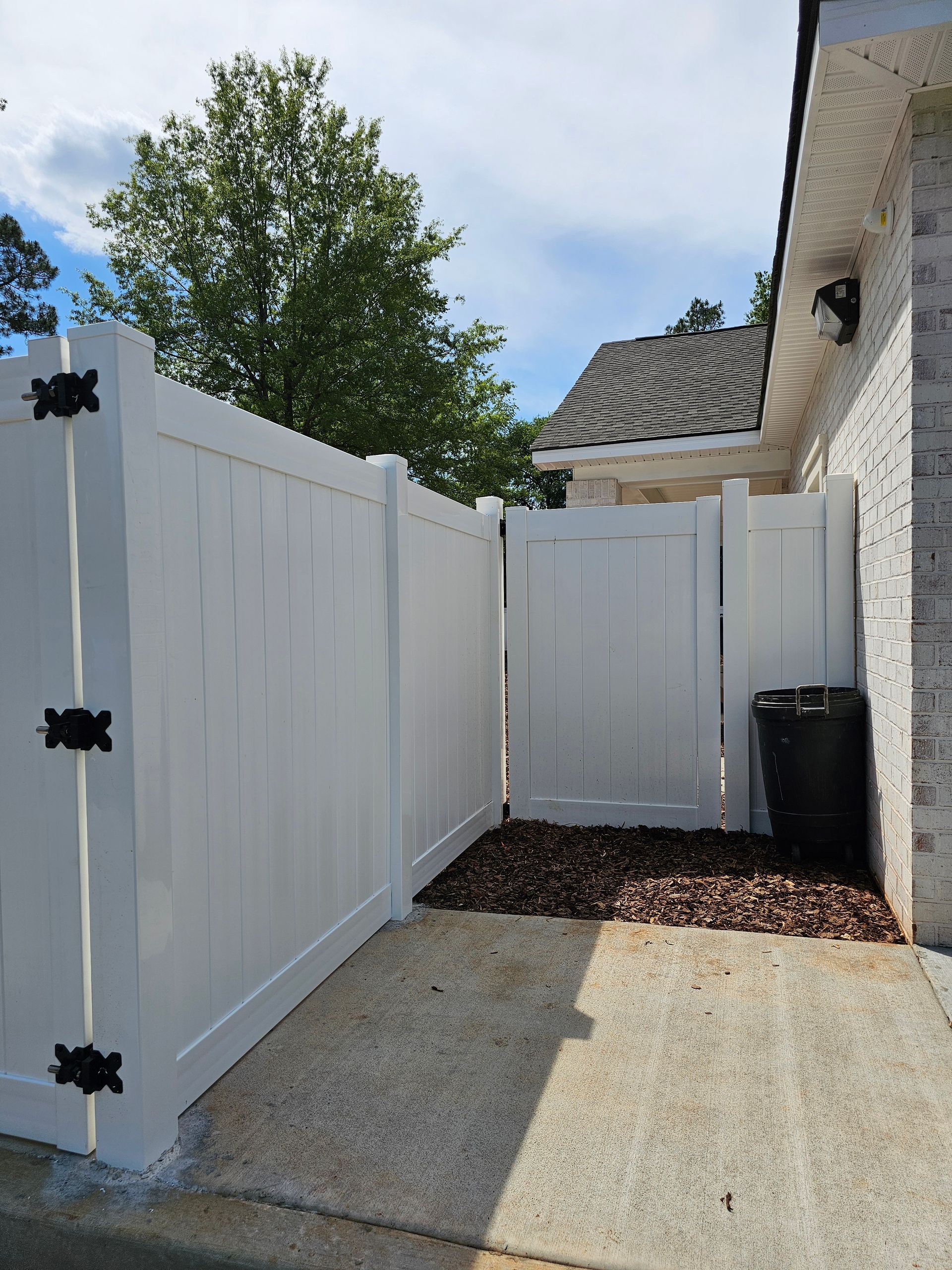 A white fence is sitting next to a brick building.