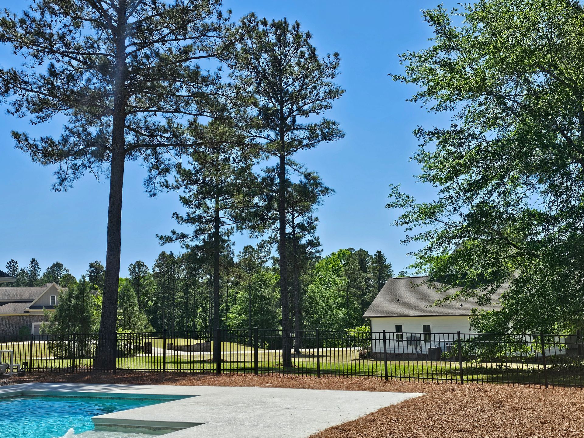 A fenced in backyard with a swimming pool and trees