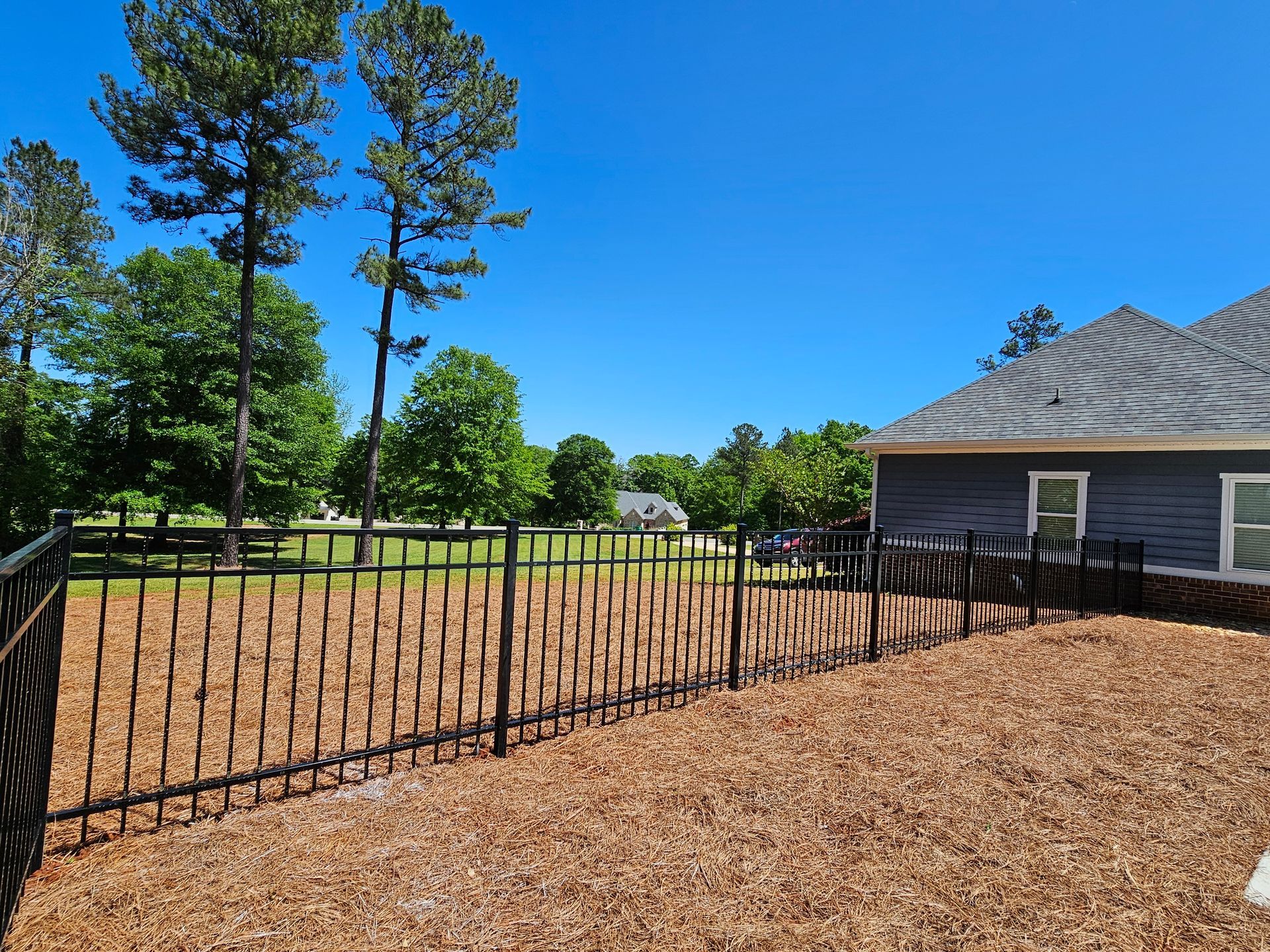 A house with a fence and a pile of mulch in front of it.