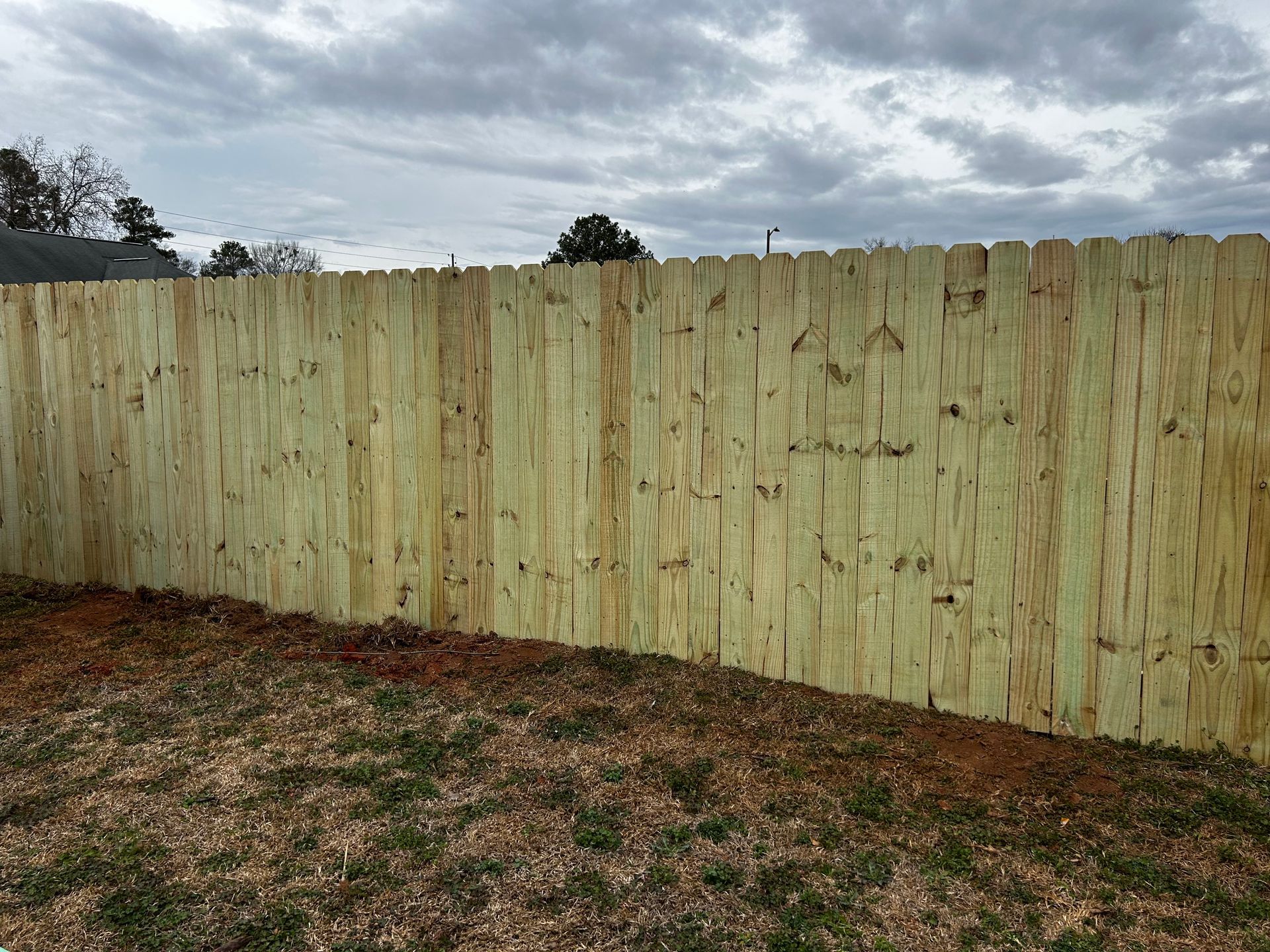 A wooden fence is in the backyard of a house.