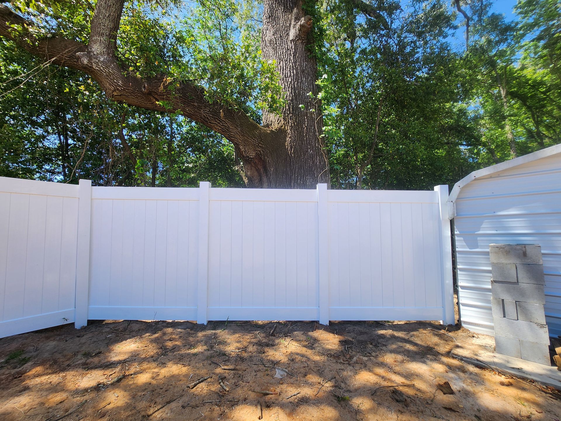 A white fence in a backyard with a tree in the background.