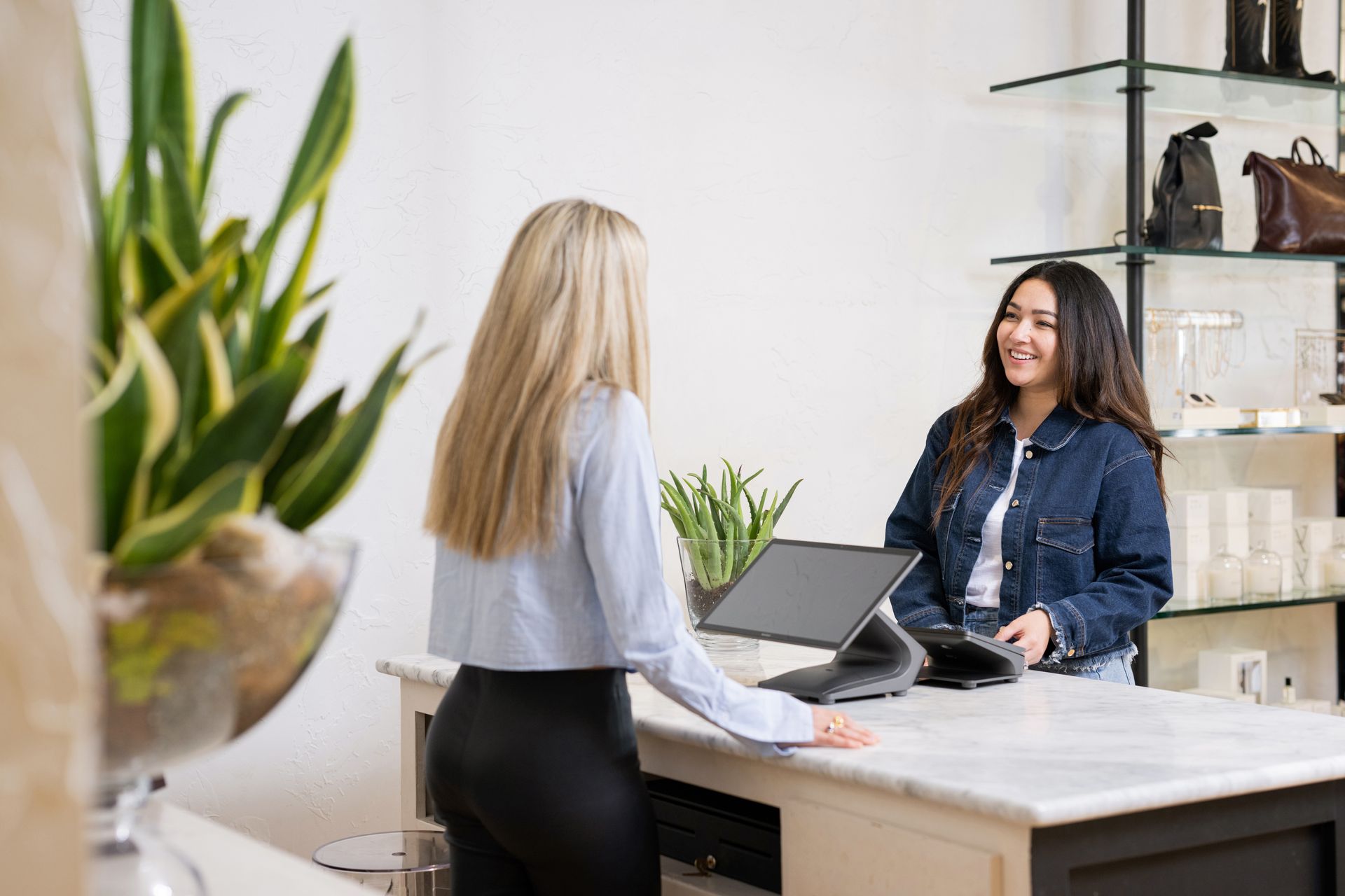 Woman at counter checking out customer in clothing store.