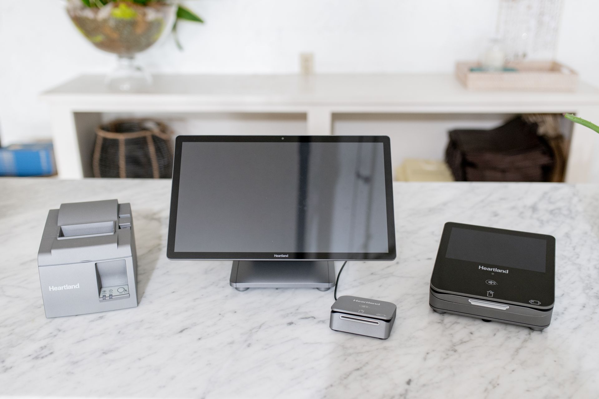Point-of-sale system on a marble counter with a monitor, receipt printer, payment terminal, and card reader.