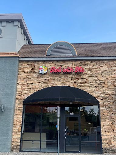 The front of a restaurant with a brick building and a sign that says `` roll with me ''.