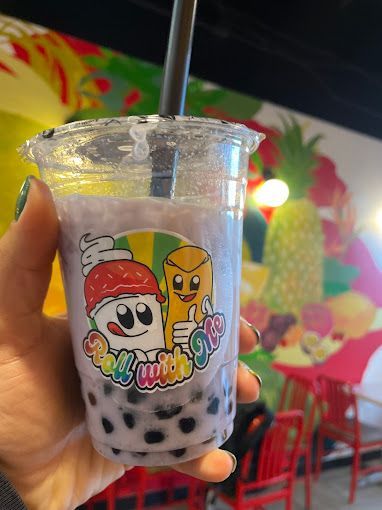 A person is holding a cup of bubble tea with a straw.