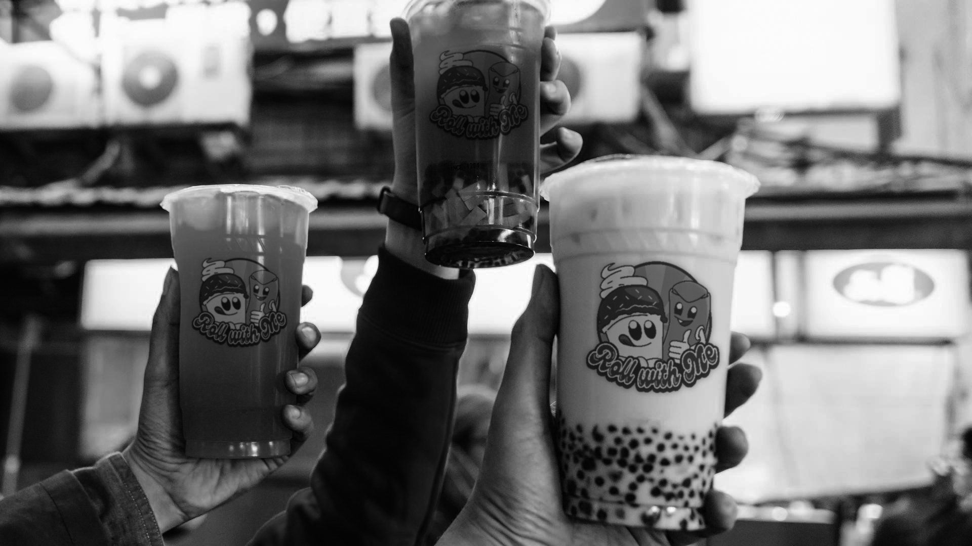 A group of people are holding up their drinks in a black and white photo.