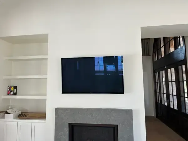 Modern living room with wall-mounted TV, fireplace, white shelves, and a hallway on the right.