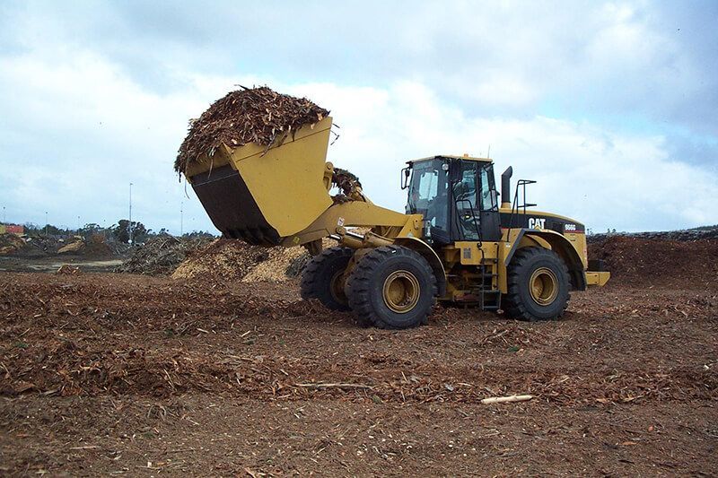 A bulldozer is loading wood chips into a bucket