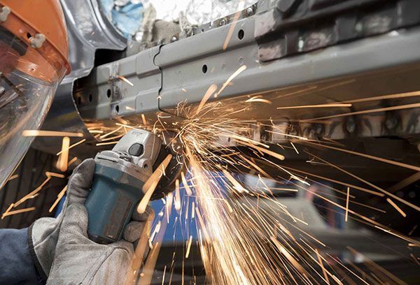 A person is grinding a piece of metal with a grinder.