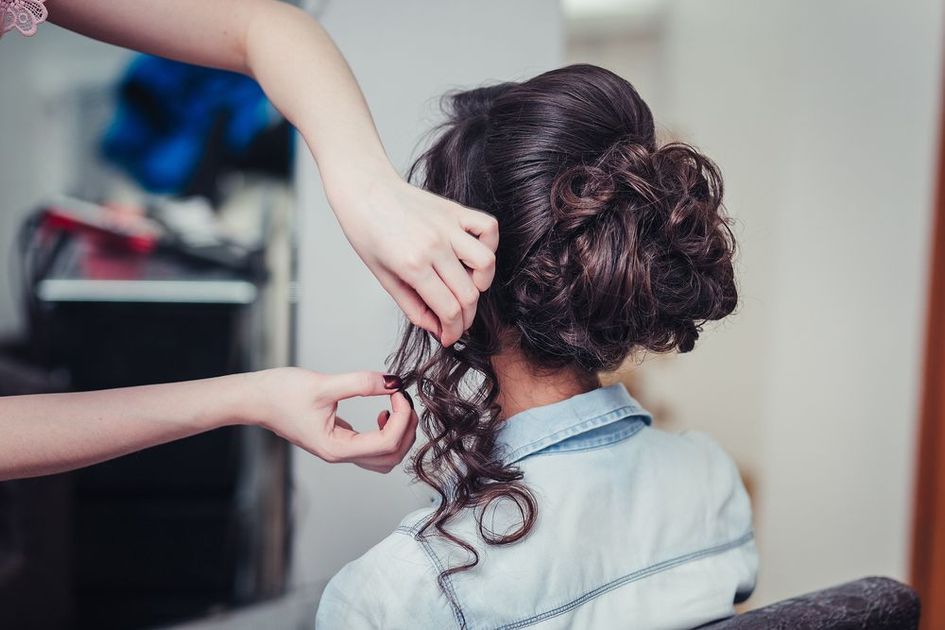 A woman is getting her hair done by a hairdresser in a salon