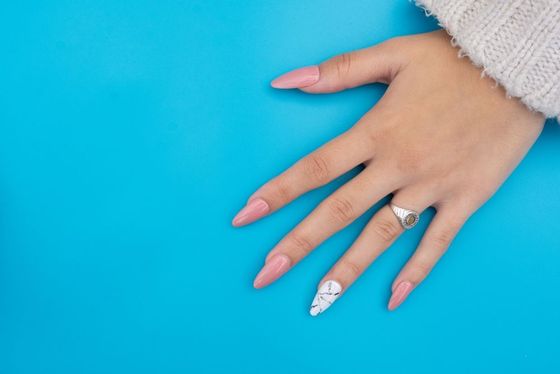A woman's hand with pink and white nails and a ring on her finger