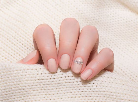 A close up of a woman's nails on a white sweater