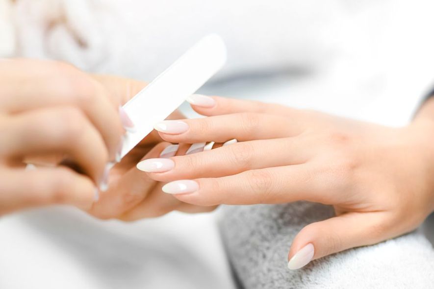 A woman is getting her nails done by a nail technician