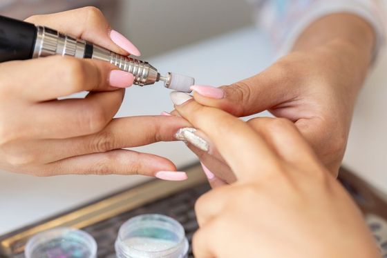 A woman is getting her nails done by a nail artist