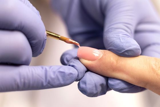 A woman is getting her nails painted by a nail artist