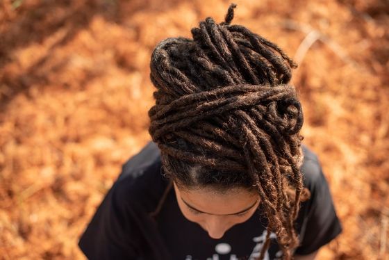 A woman with dreadlocks is standing in a pile of leaves