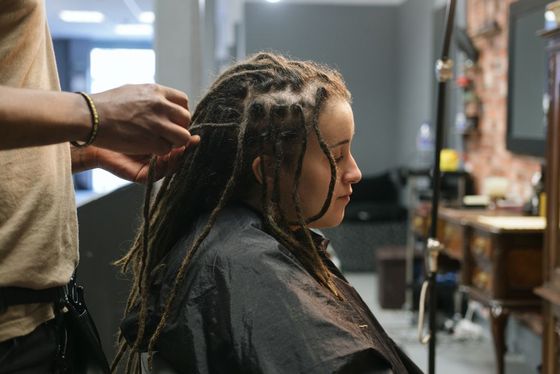 A woman is getting her hair done by a hairdresser in a salon
