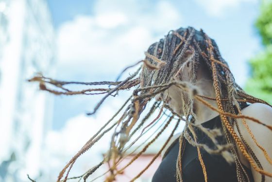A woman with dreadlocks is covering her face with her hair