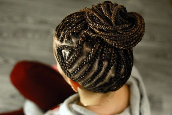 A woman with braids in a bun is sitting on a couch