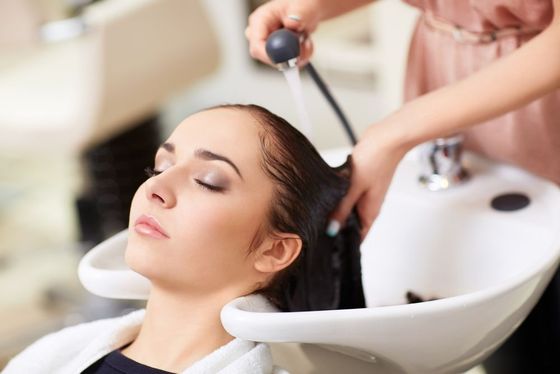 A woman is getting her hair washed at a salon