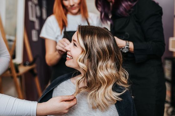 A woman is getting her hair cut by a hairdresser in a salon