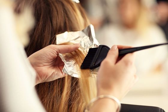 A woman is getting her hair dyed by a hairdresser