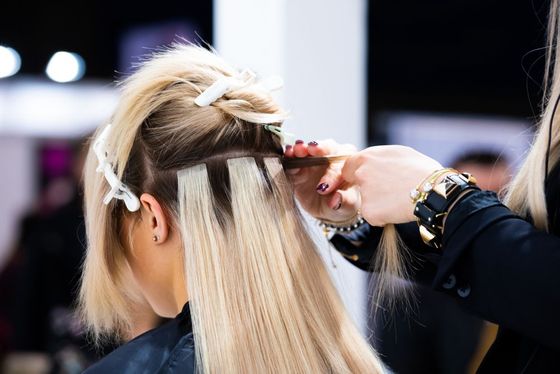 A woman is getting her hair done by a hairdresser in a salon