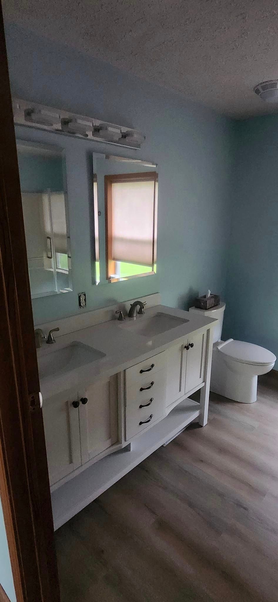 A bathroom with two sinks , a toilet and a mirror.