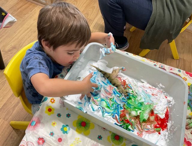 A Little Boy is Playing with Cream and a Toy Dinosaur — Coffs Harbour Childcare Info