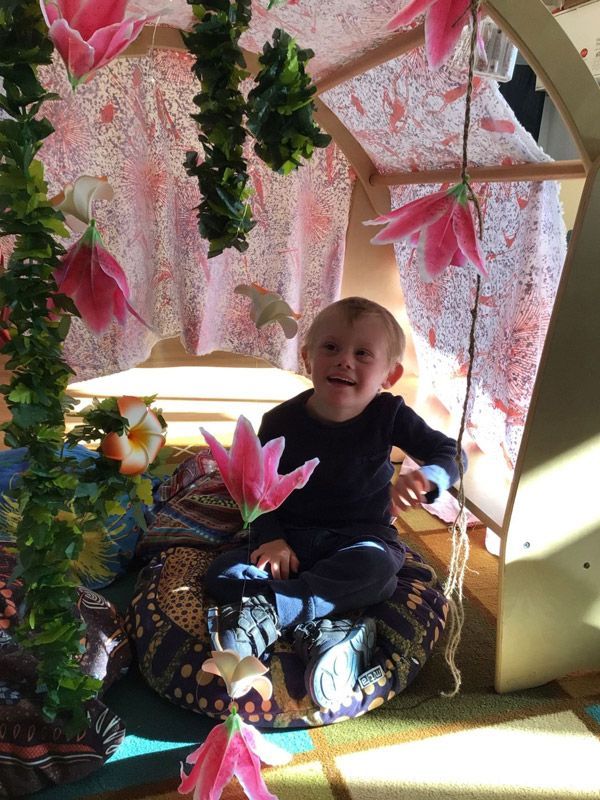 A Little Boy is Sitting on a Pillow with Flowers Hanging from the Ceiling — Enrolment Information