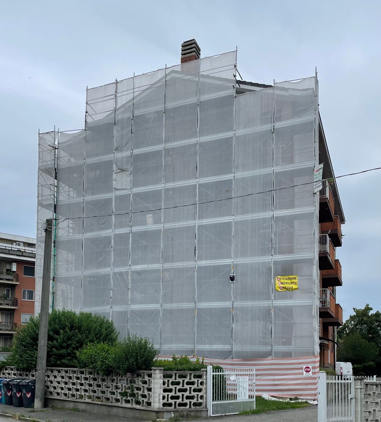 un grande edificio è coperto da impalcature e presenta un cartello giallo