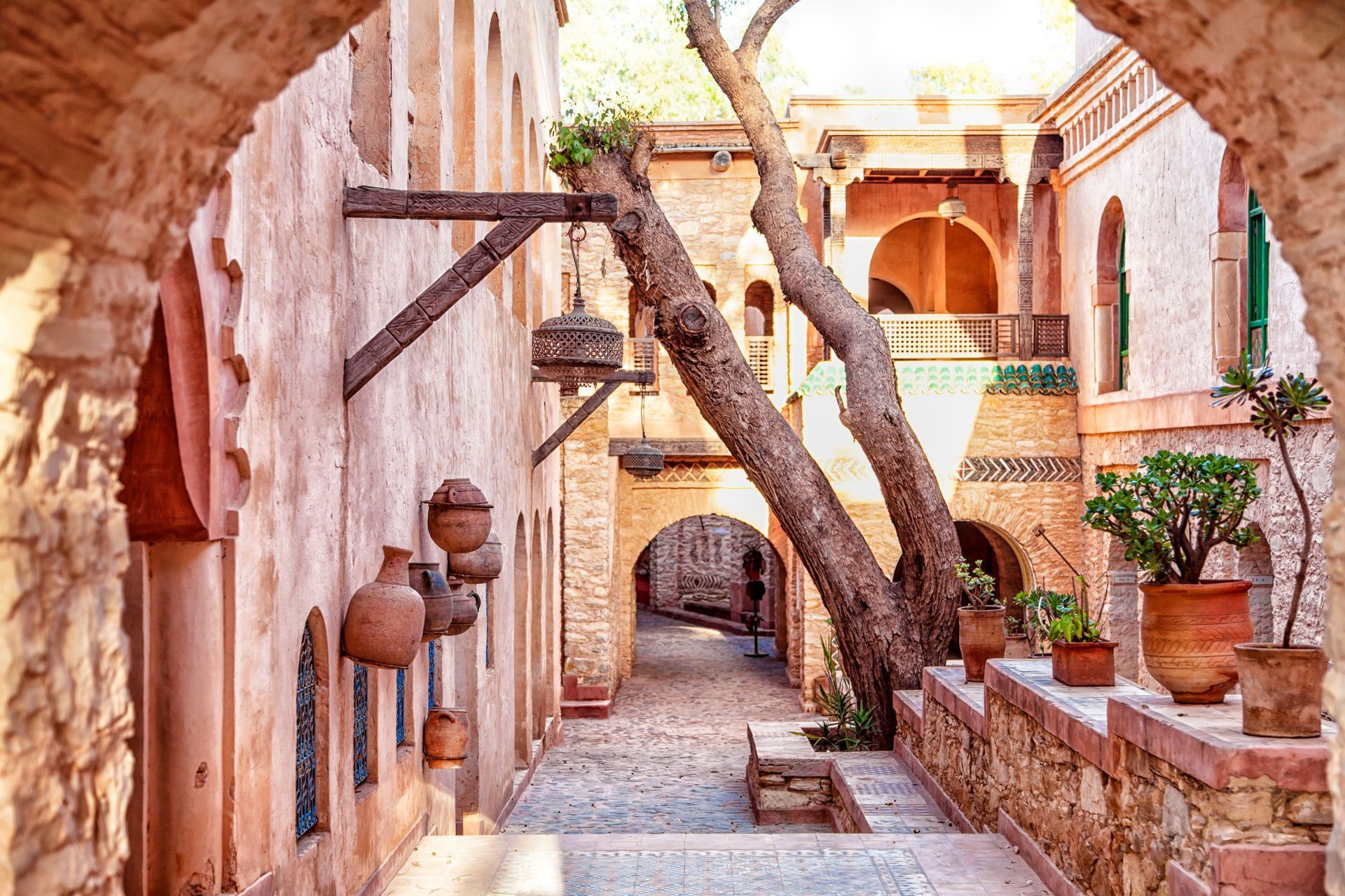 Eine schmale Gasse zwischen zwei Gebäuden mit einem Baum in der Mitte.