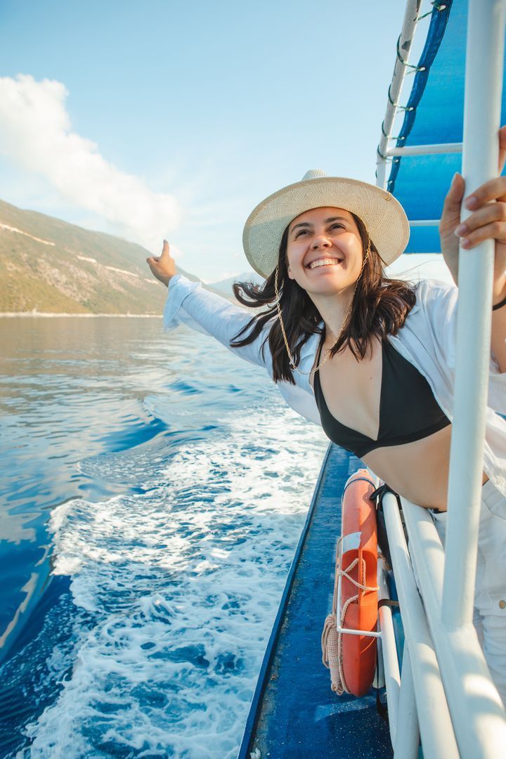 Eine Frau in Bikini und Hut fährt Boot im Meer.