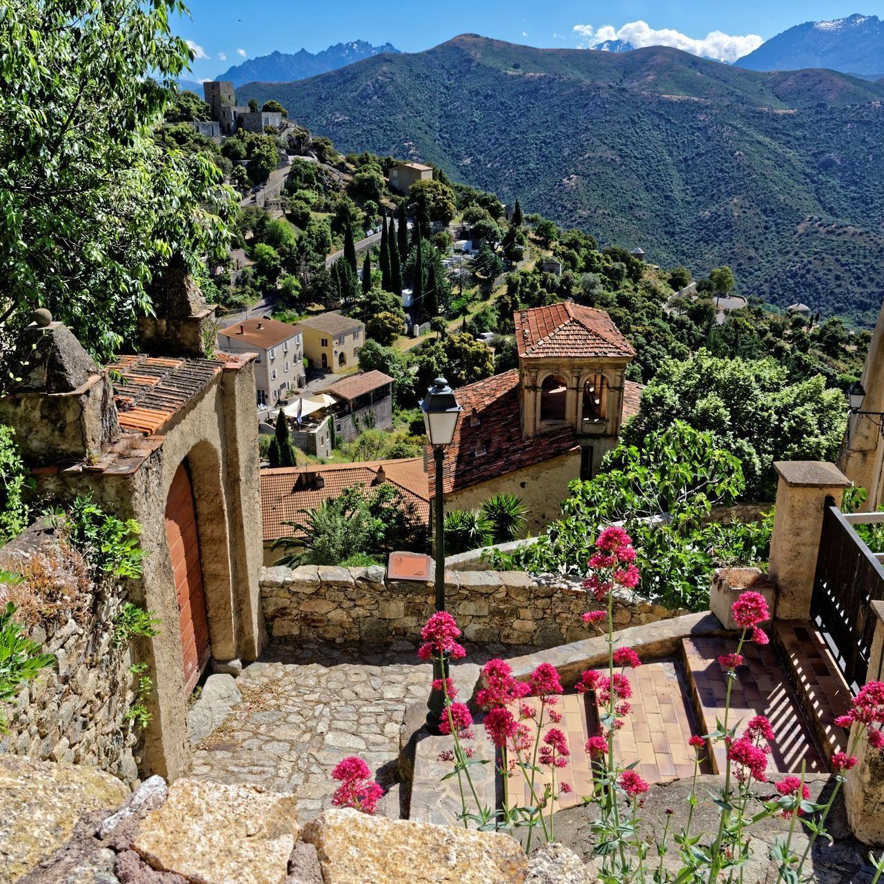 Eine Treppe, die zu einem Dorf mit Bergen im Hintergrund führt