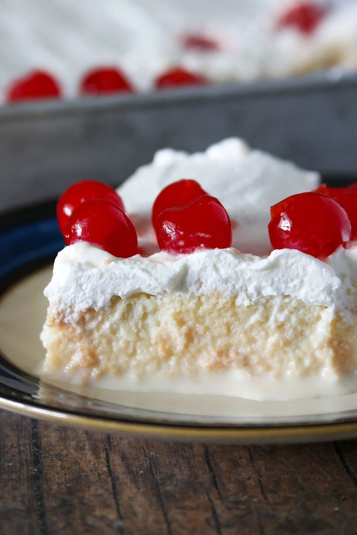 Slice of Tres Leches cake with whipped cream and cherries.