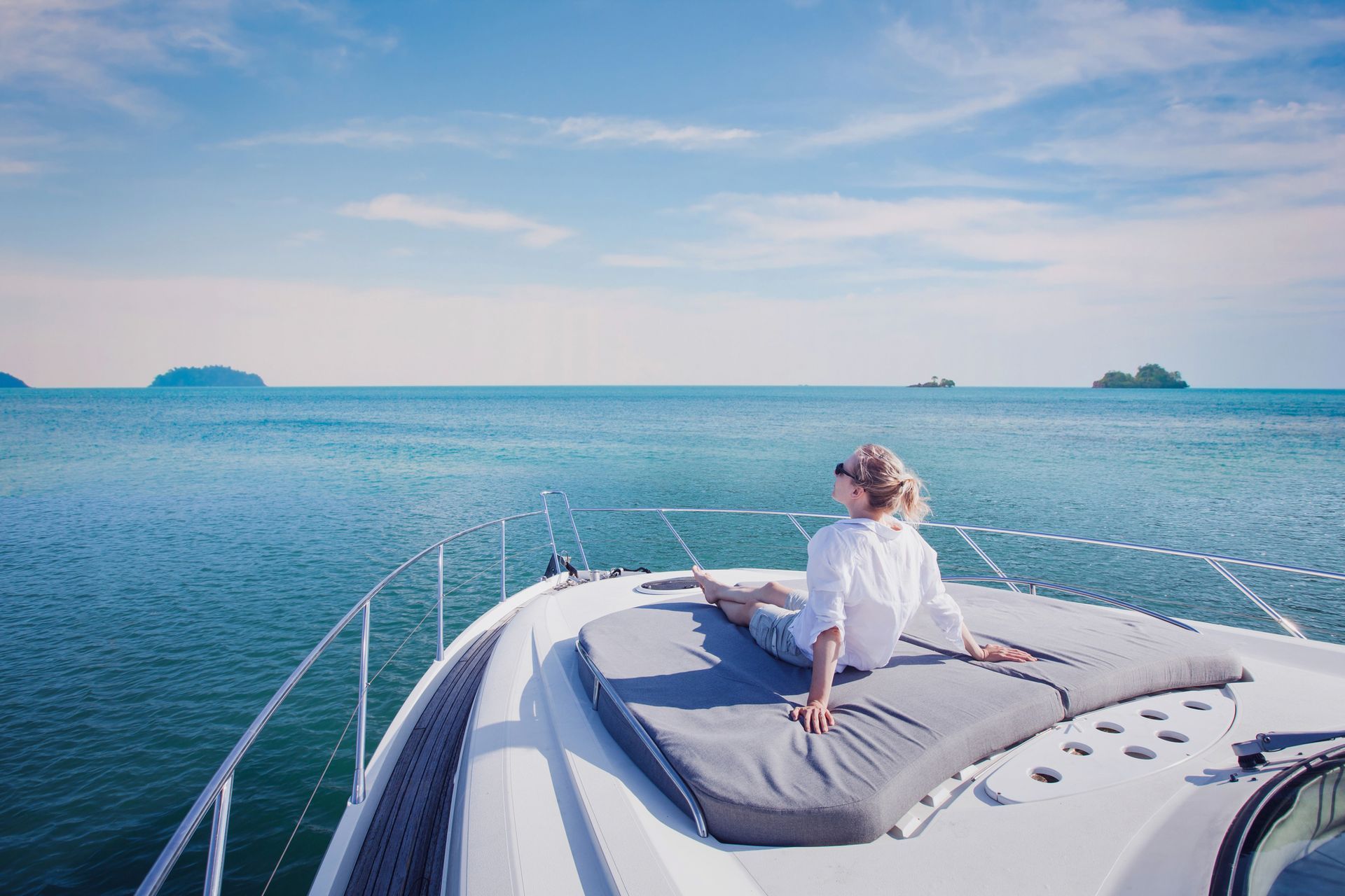 Woman relaxing on yacht, gazing at the blue ocean and sky.