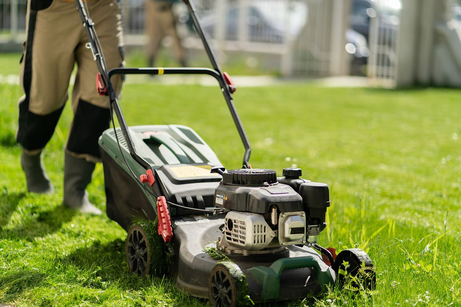 A man is mowing a lush green lawn with a lawn mower.