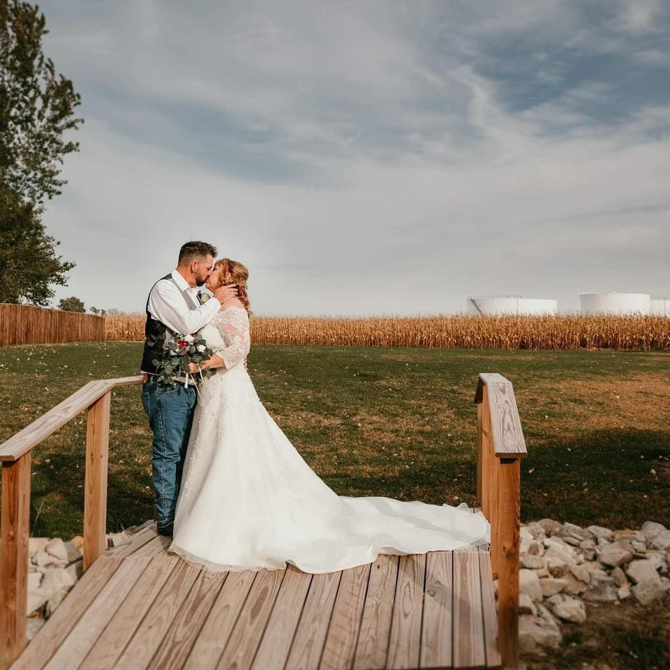 A bride and groom are kissing on a wooden bridge.