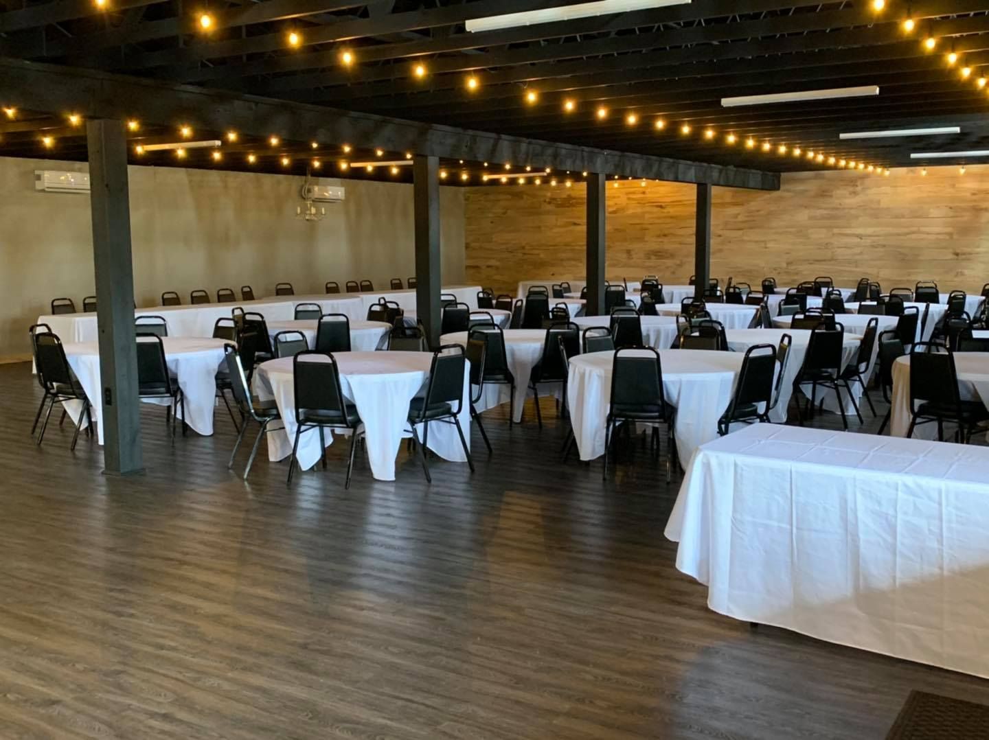 A large room with tables and chairs set up for a wedding reception.
