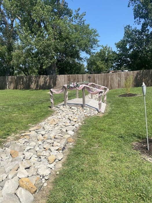 A stone path leading to a bench in a grassy yard.