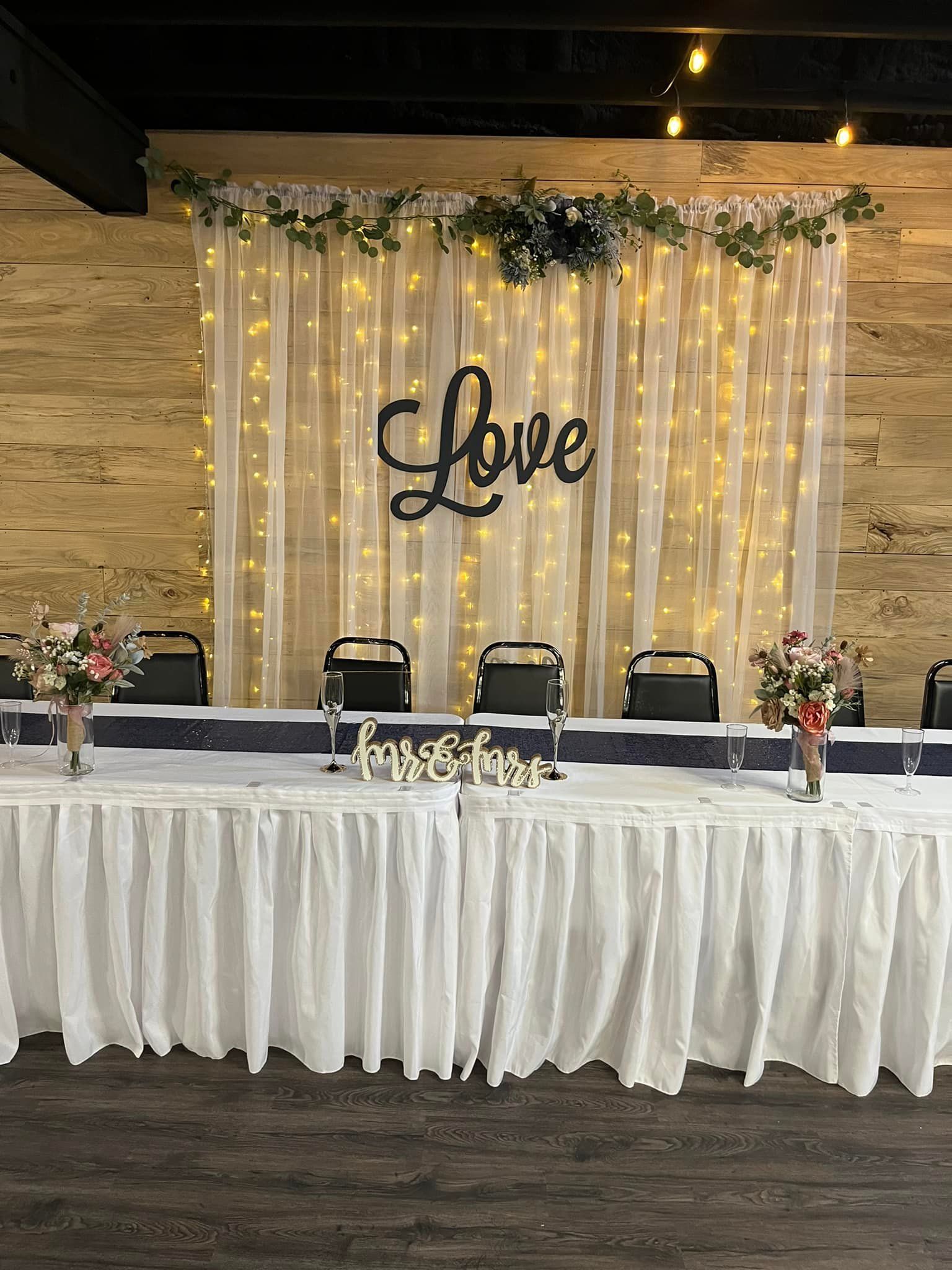 A wedding reception with a long table and a love sign on the wall.