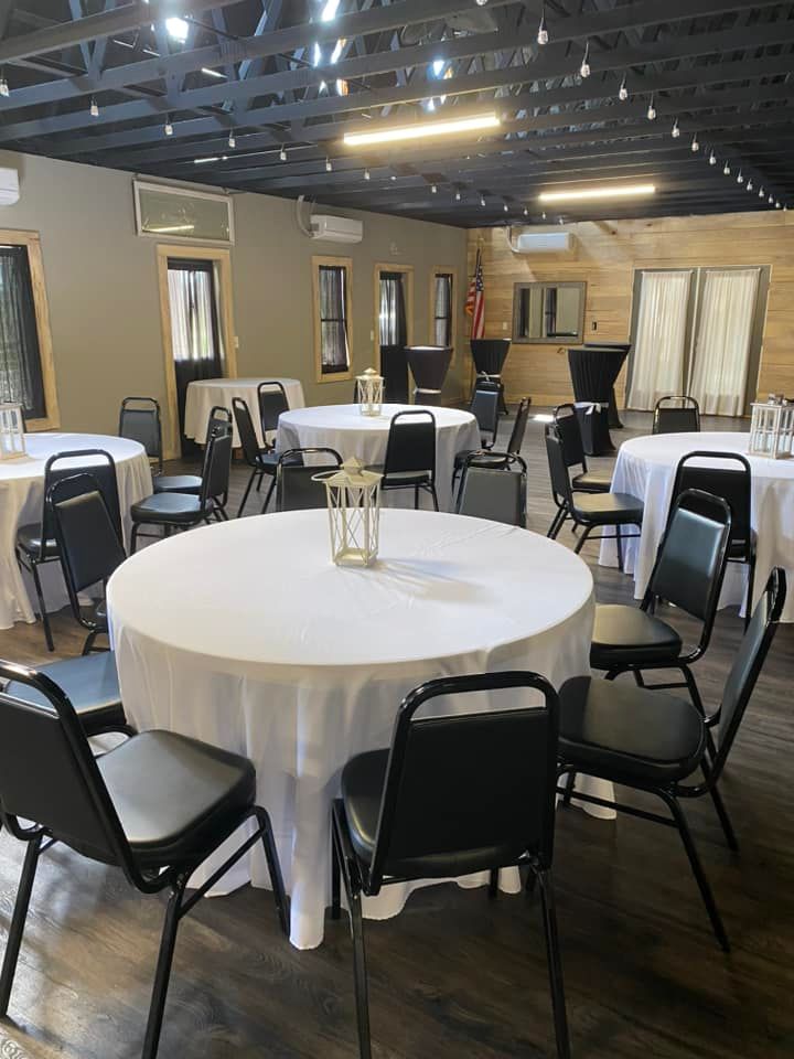 A large room with tables and chairs set up for a wedding reception.