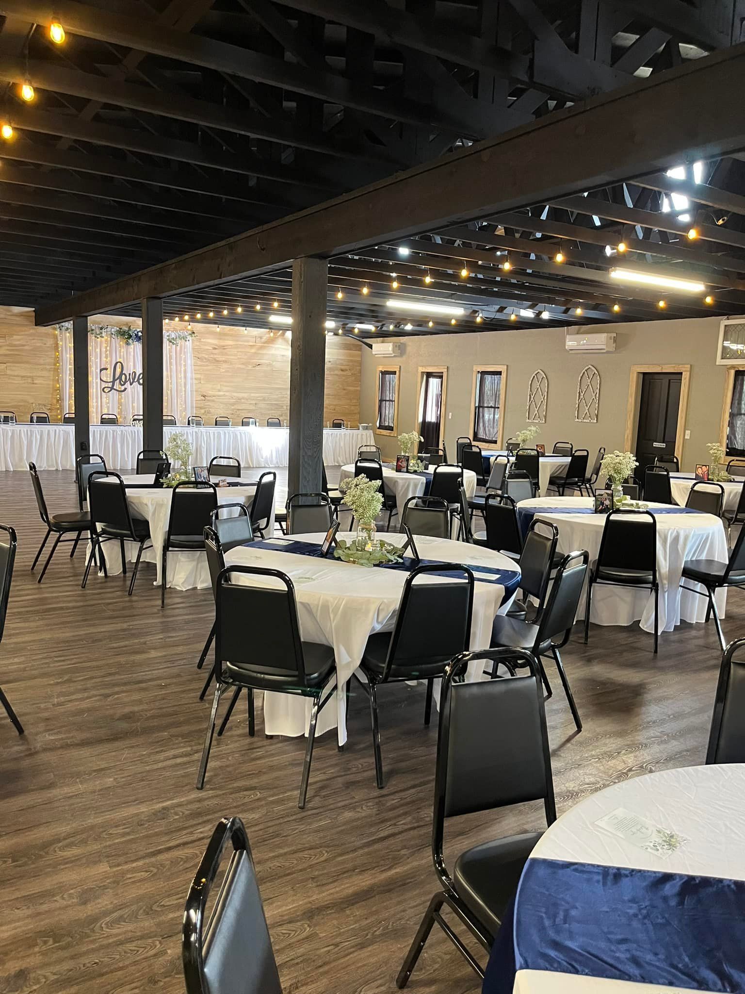 A large room with tables and chairs set up for a wedding reception.