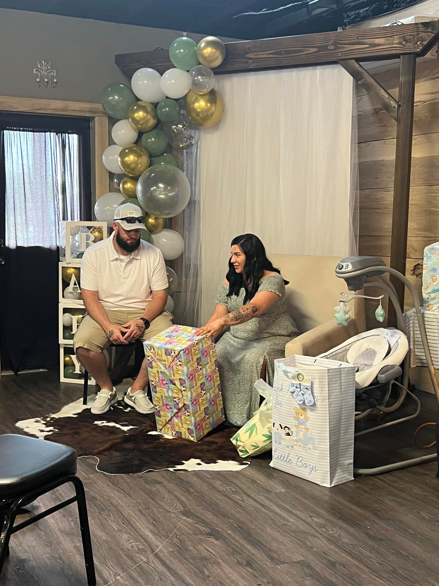 A man and a woman are sitting in a room with balloons.